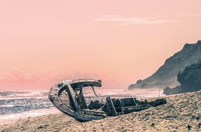 Bicycle on beach against sky during sunset