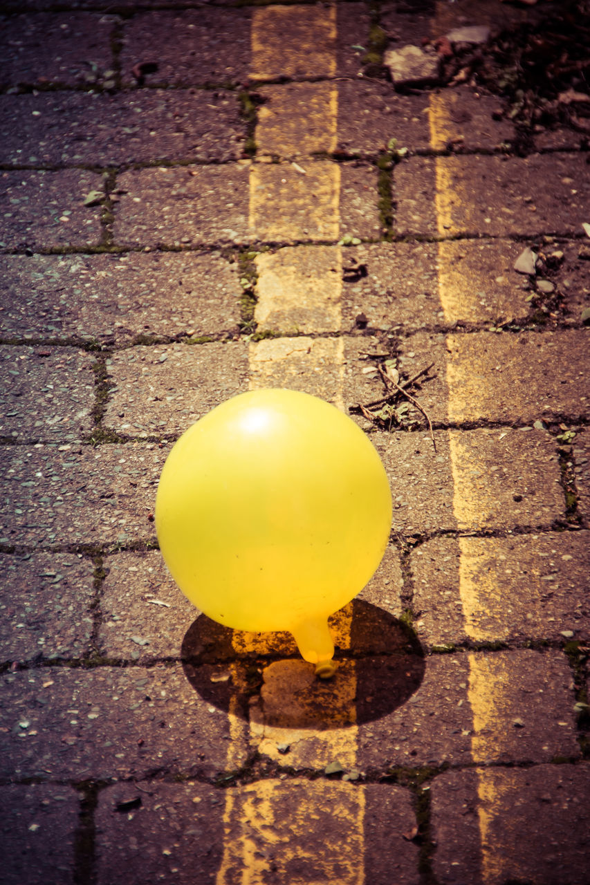 HIGH ANGLE VIEW OF YELLOW BALLS ON STREET