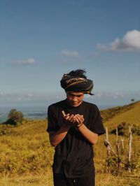 Young man standing on field against sky