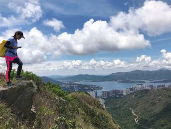 Rear view of man standing on mountain against sky