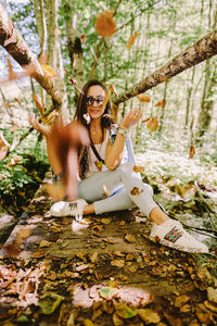 Young woman sitting on tree in forest