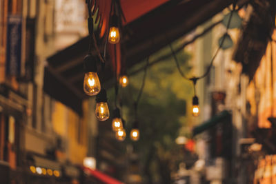 Low angle view of illuminated light bulbs hanging from ceiling in building