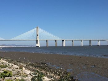 Bridge over sea against clear blue sky