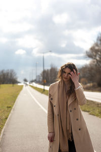 Young woman standing on road against sky