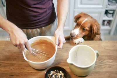 Man and dog at home in kitchen. retriever watching pet owner mixing dough to prepare sweet pie.