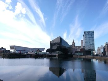 Buildings by river against sky in city