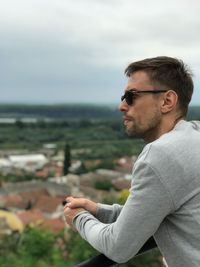 Young man looking away against sky