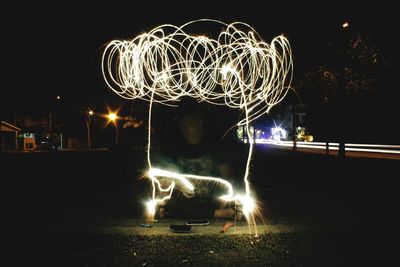 Man with sparkler making light trails at night