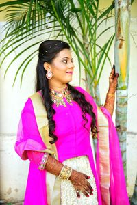 Smiling young woman standing against pink umbrella