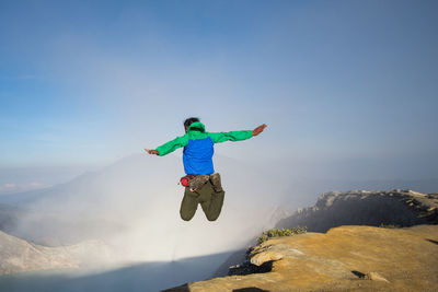 Man jumping in mountain against sky