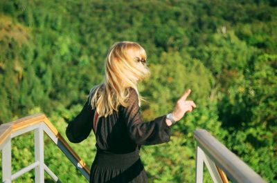 Woman standing by railing against trees