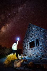 Man standing by building against sky at night