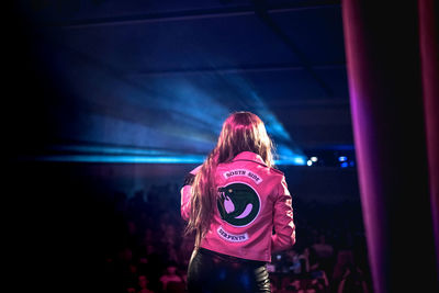 Rear view of woman standing against illuminated stage