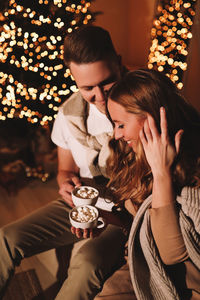 A romantic couple in love celebrates christmas holidays and new year in a cozy house at night