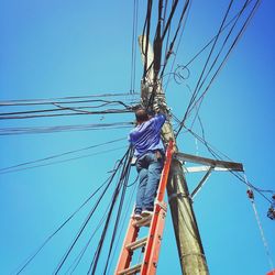 Low angle view of power lines against clear blue sky