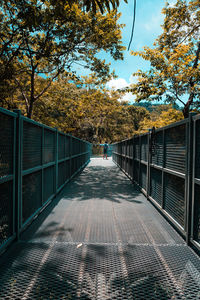 Footpath by footbridge in park against sky