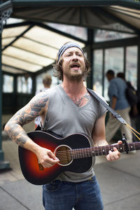 Man singing while playing guitar on street