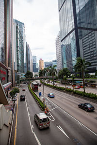 Traffic on city street by buildings against sky