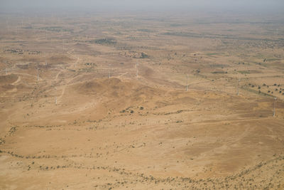 High angle view of desert land with large group of wind turbines