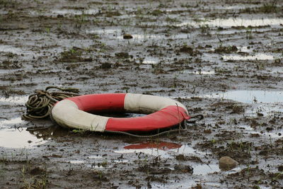 High angle view of abandoned life belt and rope on muddy field