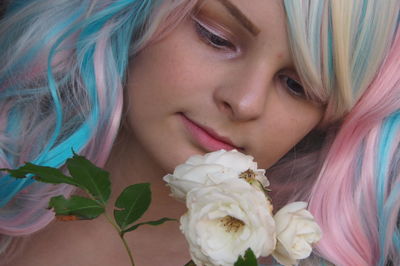 Close-up of teenage girl with dyed hair looking at roses