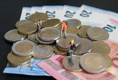 Miniature figurines of worker working on a pile of money