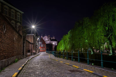 Street by buildings against sky at night