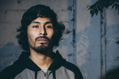 Portrait of young man standing against wall