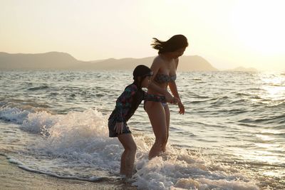 Full length of woman on beach against sky during sunset