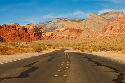 Road by mountains against sky