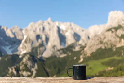 Camping tin mug on the wooden railing on the mountains background. hiking concept