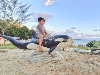 Side view of boy on beach against sky