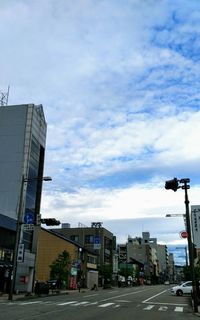 Road by buildings in city against sky