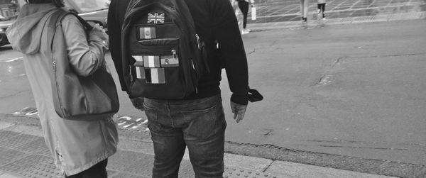 Rear view of people walking on sidewalk in city