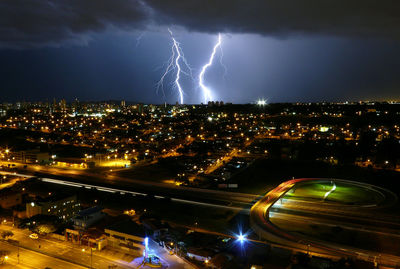 Lightning over cityscape against sky at night