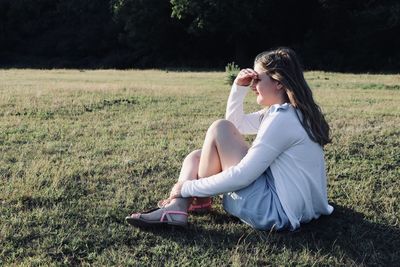 Side view of girl sitting on field