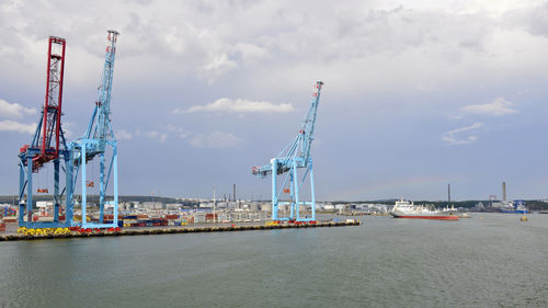 Cranes at commercial dock against sky