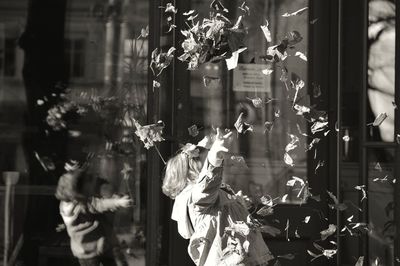 Girl throwing dry leaves in mid-air at city