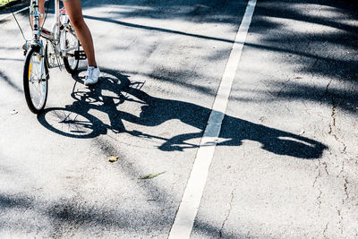 Low section of woman sitting on bicycle on road