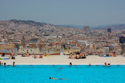 People in swimming pool against buildings in city