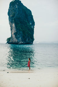 Mid distance view of woman standing at beach against rock formation at ko samui