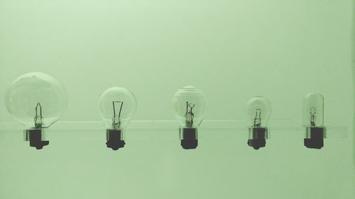 Close-up of various light bulbs against green background