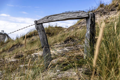 Barbed wire fence on field against sky