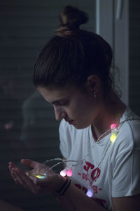 Side view of woman looking while holding illuminated lights