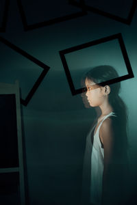 Double exposure of girl looking away while standing against wall at home