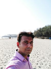 Portrait of young man on beach against clear sky