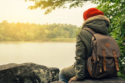 Rear view of couple sitting on riverbank against sky