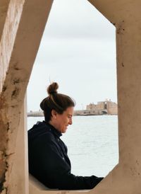 Side view of young woman looking through window