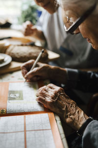 Senior woman solving crossword puzzle in book at table