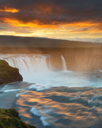 Scenic view of waterfall against sky during sunset